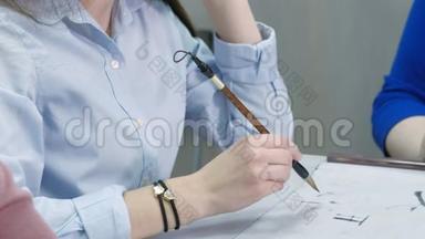 女子教青少年如何在<strong>书法</strong>课上写汉字。 学生<strong>用毛笔</strong>、墨水和